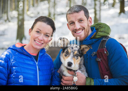 Portrait glückliches Paar mit Hund Wandern im Wald Stockfoto