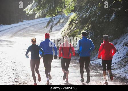 Familie Jogging auf Trail im sonnigen, verschneiten Wald Stockfoto