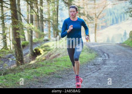 Frau joggen auf Trail im Wald Stockfoto