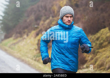 Konzentriert man joggen auf dem Weg in den regnerischen Wald Stockfoto