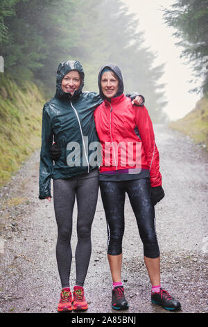 Portrait glückliche Mutter und Tochter Wandern auf Trail im regnerischen Wald Stockfoto