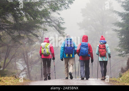 Familie mit Wanderstöcken Wandern auf Trail im regnerischen Wald Stockfoto