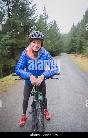 Porträt Frau Mountainbiken auf Trail in abgelegenen Wäldern Stockfoto