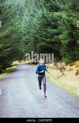 Frau läuft auf Trail in abgelegenen Wäldern Stockfoto