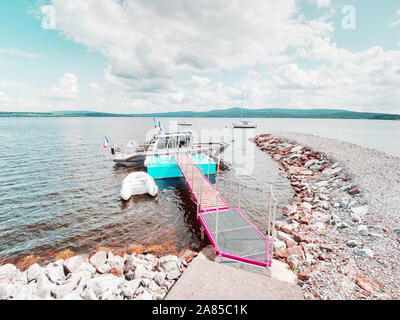 Gummibärchen Motor Boot und Motor Schiff auf Steel Pier durch ein Seil und andere Boot im Hintergrund verankert Stockfoto