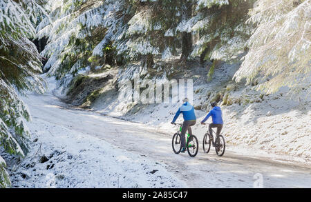 Paar Mountainbiken auf Remote, verschneiten Trail im Wald Stockfoto