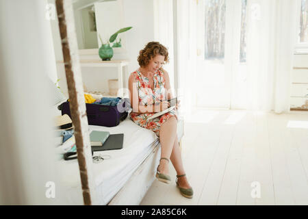 Frau schreiben im Journal weiter am Strand Hütte Schlafzimmer zu Koffer Stockfoto