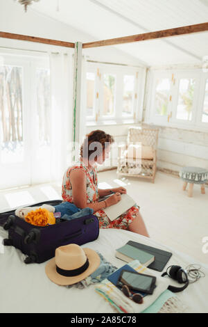 Frau schreiben im Journal nächste in Beach Hut Schlafzimmer zu Koffer Stockfoto