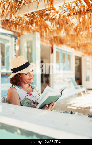 Frau liest Buch über Beach Hut Terrasse Stockfoto