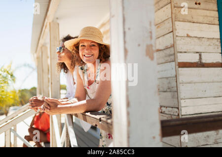 Portrait glückliche Frau an sonnigen Strand Hütte Terrasse Stockfoto