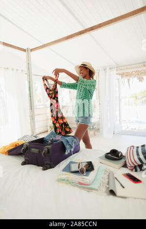 Glückliche Frau Auspacken der Koffer im Beach House Schlafzimmer Stockfoto