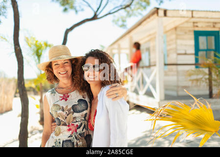Portrait glückliche Mutter und erwachsene Tochter außerhalb Sunny Beach Hut Stockfoto