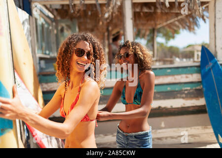 Glückliche junge Frauen mit Surfbrettern auf Sunny Beach Stockfoto
