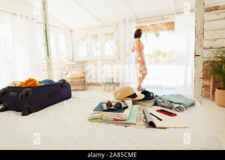 Frau, die in der Hütte Tür über Koffer und Habseligkeiten auf dem Bett Stockfoto