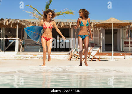 Unbeschwerte junge Frauen Freunde mit Surfbrett auf Sunny Beach Stockfoto