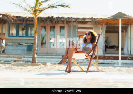 Ruhige junge Frau im Bikini Sonnenbaden am sonnigen Strand Stockfoto