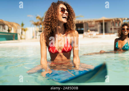 Glückliche junge Frau auf Surfboard im sonnigen Ozean Stockfoto