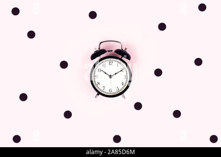 Alarm Clock vintage auf einem rosa Hintergrund von Konfetti umgeben. Flach, Ansicht von oben, kopieren. Stockfoto