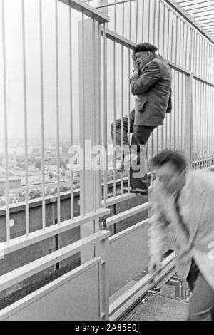 Der Fotograf Erich Andres sucht sich in einem Absperrgitter und Beispiele hängend, den Blick für sein Foto von Berlin, Deutschland 1984. Fotograf Erich Andres hängen in einem Schutzgitter die beste Ansicht für sein Foto, Berlin, Deutschland 1984 zu finden. Stockfoto