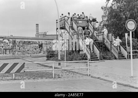 Touristen riskieren von einer Aussichtsplattform am Potsdamer Platz einen Blick in den Ostteil von Berlin, Deutschland 1984. Touristen mit Blick auf die östlichen Teile von Berlin Von einer Aussichtsplattform am Potsdamer Platz, Deutschland 1984. Stockfoto