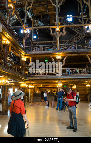 Reisende in der Lobby des historischen Old Faithful Inn, einschließlich Rezeption Stockfoto