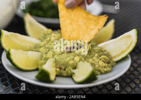 Tortilla Eintauchen in zertrümmert, Avocado, grüne Guacamole dip Stockfoto