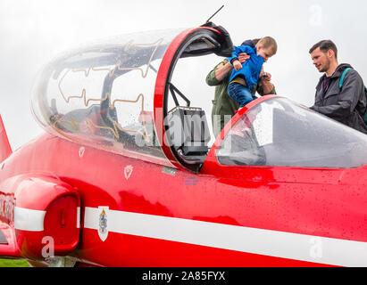 Junge sitzt in roter Pfeil BAE Systems Hawk Flugzeug auf dem Display, der Nationalen Airshow, East Fortune, East Lothian, Schottland, Großbritannien Stockfoto