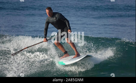 Athletischer Mann (52 jährige Kaukasier) bleibt fit und aktiv Surfen auf einem SUP (Stand up Paddle Board) Stockfoto