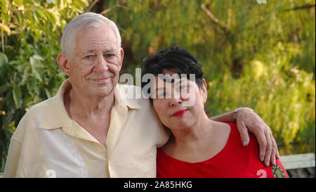 Glücklich, älteres Paar lächelnd. Der Mann (80 Jahre alt) hat seinen Arm um die Schulter, seine Frau (62 Jahre alte Hispanic). Stockfoto