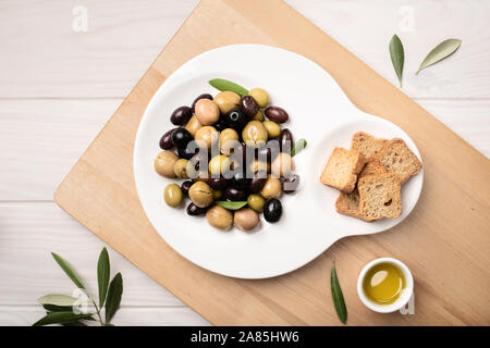 Marinierte Oliven in der Platte auf hölzernen Tisch. Leckere mediterrane Küche. Spanische Tapa Stockfoto