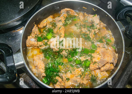 Fleisch mit Zwiebeln, Karotten, Dill und Lorbeerblatt ist geschmort in eine Pfanne geben. Home Kochen Stockfoto