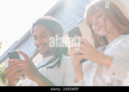 Foto eines multiethnischen Paar an Ihrem Telefon Seite an Seite Stockfoto