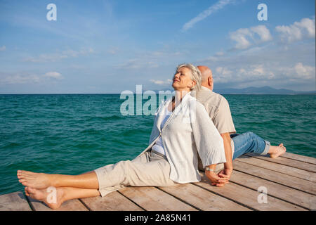 Senior Paar sitzt auf einem Pier Stockfoto