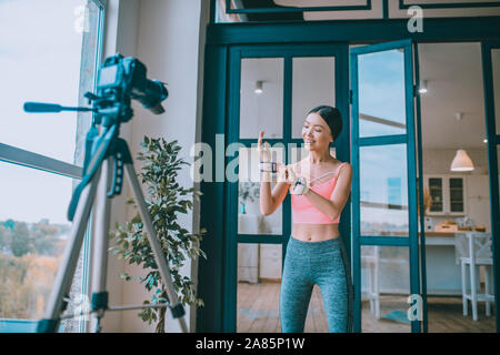 Dunkelhaarige Fitness Trainer ihren Arm Gewichtsmanschetten angezeigt Stockfoto