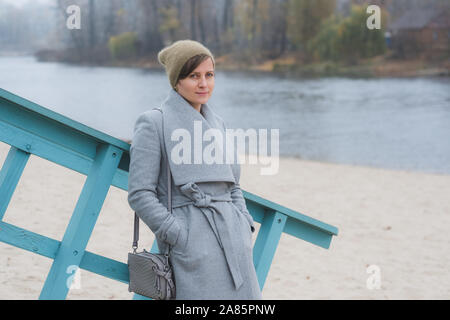 Junge Frau allein zu Fuß trägt einen grauen Mantel Stockfoto