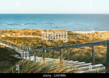 Sommer Marine mit einer Treppe gehen durch Dünen mit Gras, auf dem Weg zur Nordsee, Sylt, Deutschland. Sonnigen Küste Landschaft. Boardwalk. Stockfoto