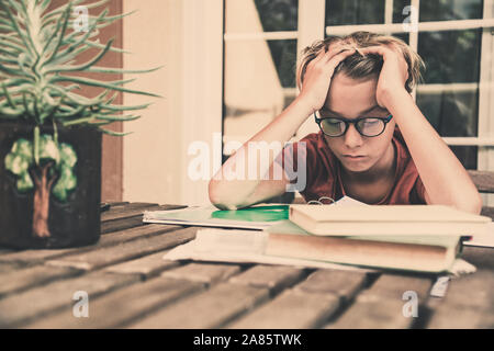 Müde Schüler Hausaufgaben zu Hause sitzen im Freien mit Schule Bücher und Zeitungen. Junge müde wegen der schweren studieren. Kind schlafend auf dem copybook Stockfoto