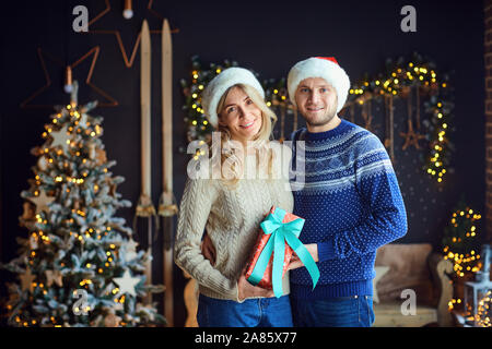 Der Mann und die Frau mit Geschenken in einem Raum zu Weihnachten. Stockfoto