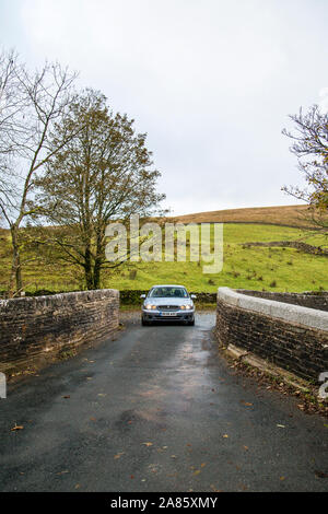 Ein Jaguar Limousine überquert die Brücke über den Fluss Dee an Cowgill, Dentdale, North Yorkshire, Großbritannien Stockfoto