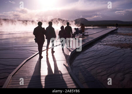 Besucher sind gegen die Sonne ab- und aufsteigenden Dampf im Grand Prismatic heißen Quellen im Yellowstone National Park, Wyoming, USA Stockfoto