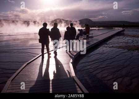 Besucher sind gegen die Sonne ab- und aufsteigenden Dampf im Grand Prismatic heißen Quellen im Yellowstone National Park, Wyoming, USA Stockfoto