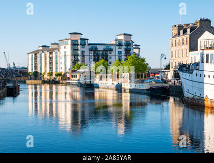 Apartment Block und Boot Reflexionen, Wasser von Leith Fluss in der Dämmerung, am Ufer, Leith, Edinburgh, Schottland, Großbritannien Stockfoto