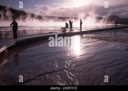 Besucher sind gegen die Sonne ab- und aufsteigenden Dampf im Grand Prismatic heißen Quellen im Yellowstone National Park, Wyoming, USA Stockfoto