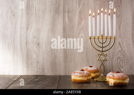 Jüdischen Hanukkah Menorah und sufganiyot Donuts auf Holztisch. Copyspace Stockfoto