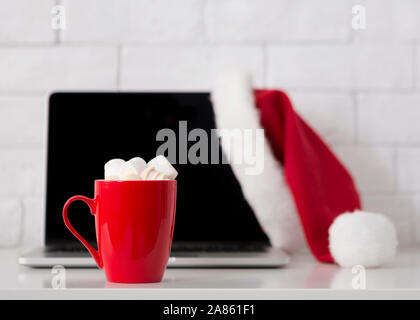 Trinken Sie heiße Schokolade und Arbeiten am Laptop, weihnachtliche Stimmung Stockfoto