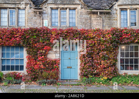 Parthenocissus Tricuspidata. Boston Ivy/Japanische Kriechgang im Herbst auf einem Cotswold Cottage in Burford, Cotswolds, Oxfordshire, England Stockfoto