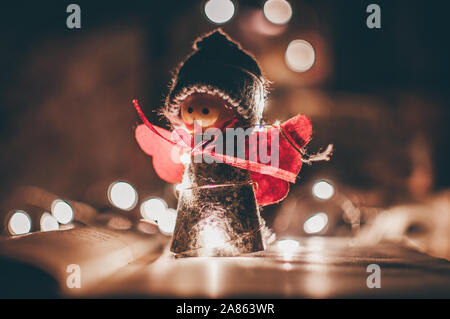 Holz Engel Weihnachten Girlande steht auf einem Buch, im Hintergrund ist eine LED-Kranz. Weihnachten Konzept. Stockfoto