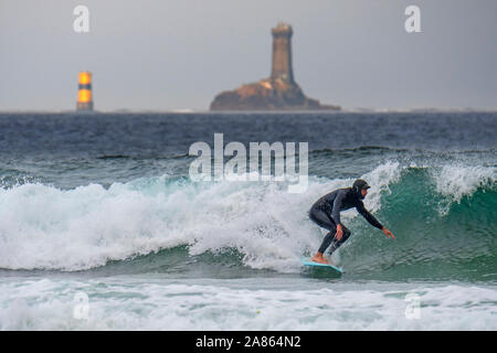 Leuchtturm La Vieille und Surfer in Neoprenanzug Reiten eine Welle auf Surfbrett an der Pointe du Raz, Finistère, Bretagne, Frankreich Stockfoto