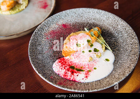 Frischen saftigen Lachs auf einem Kissen mit pikanter Sauce auf einer Platte Stockfoto