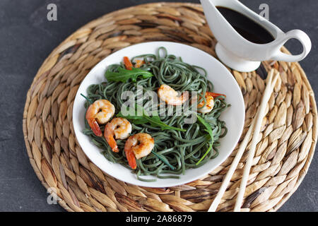 Soba spirulina Nudeln mit Garnelen auf einem weißen Teller Ansicht von oben. Asiatische Küche kreatives Konzept. Stockfoto